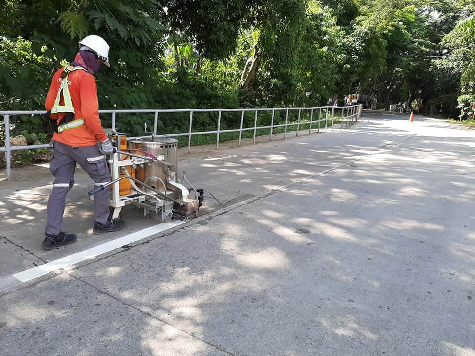Road contractor applying white road marking paint