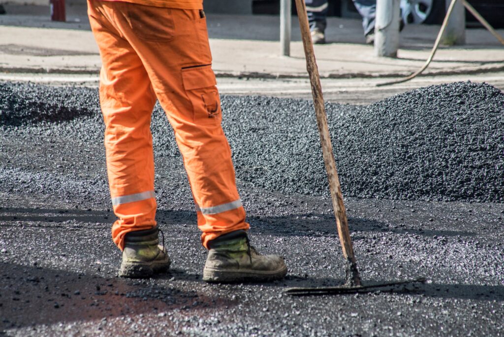 a road worker putting in cold mix asphalt